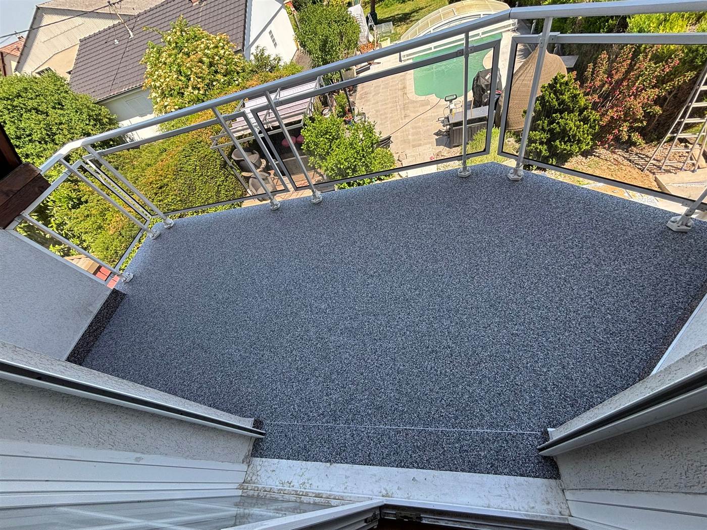 Terrasse en moquette de pierre surplombant une piscine
